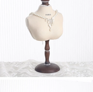 Close-up of vintage pearl necklace with lace flower pendant on portrait jewelry stand