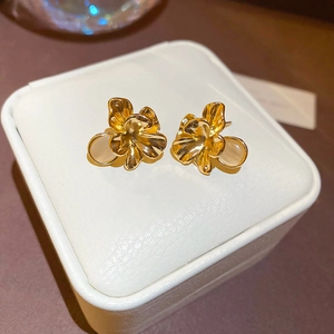 Macro shot of gold floral earrings with cat eye stone on a white leather jewelry box lid