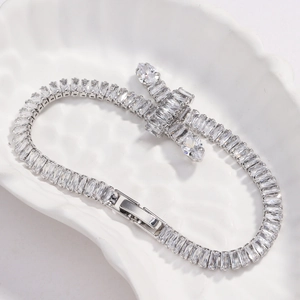 Detailed macro of a silver zircon cross bracelet on an embossed shell textured ceramic plate