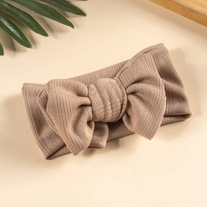 Detail of warm brown knitted baby headband featuring a large double-layer textured bow