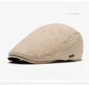 Close-up of beige knit newsboy hat with refined side metal brand plate and texture
