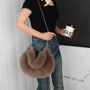 Detail of plush brown faux fur shoulder bag with metallic chain strap worn by a model