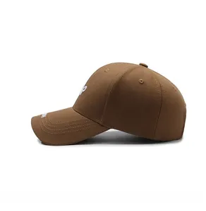 Détail d'une casquette en coton marron foncé avec broderie blanche sur la visière courbée