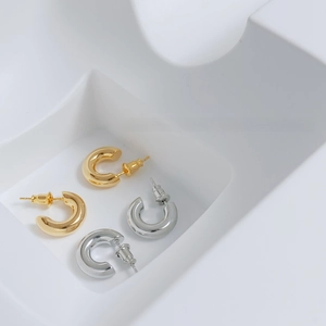 Top view of gold and silver polished C-shaped hoop earrings on a geometric stand