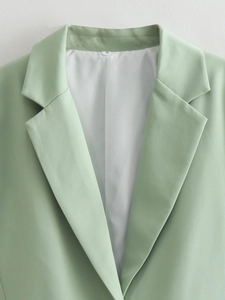 Detail of mint green V-neck blazer showing precise lapel stitching and woven texture