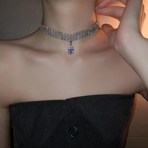 Close-up of a silver rhinestone choker necklace with a crystal drop on a female model