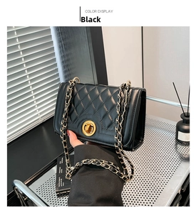Close-up of black quilted shoulder bag with gold twist lock and metal chain strap