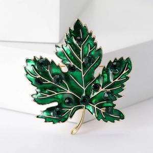 Macro shot of maple leaf brooch with green enamel and emerald green rhinestones
