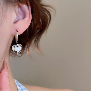 Close-up of a polka dot heart dangle earring worn on the ear featuring a small red heart