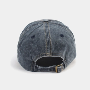 Detail of washed denim baseball cap featuring vintage bronze metal buckle and yellow stitching