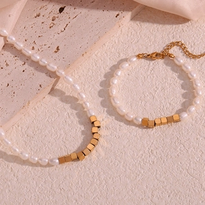 Detail of freshwater pearl necklace and bracelet set with golden cubic beads on stone