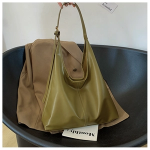 Detail of an olive green soft leather shoulder bag placed on a modern black chair