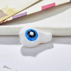 Macro shot of a teardrop-shaped white resin Evil Eye bead for DIY jewelry making