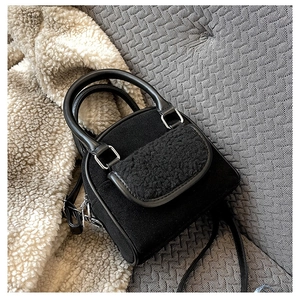 Detail view of black plush handbag with PU leather handles and adjustable shoulder strap
