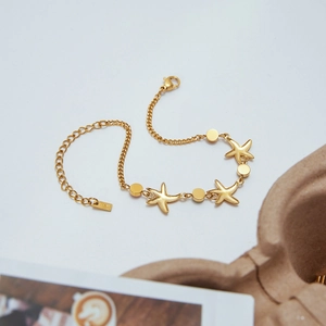 Macro detail of golden starfish charms and stainless steel clasp on the gold bracelet