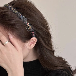 Dettaglio del cerchietto in maglia nera con punti colorati per un effetto capelli voluminosi