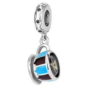 Detail view of a silver teacup charm with blue enamel patterns and a faceted gemstone
