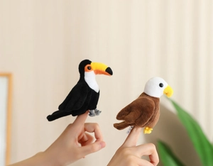 Close-up of plush toucan and eagle finger puppets on hand with soft texture detail