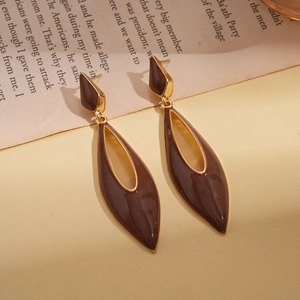 Detail of vintage brown enamel teardrop earrings with gold rim on a book background
