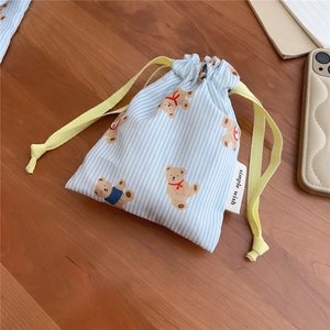 Detailed view of blue striped cotton drawstring bag with cute bear print on wooden table