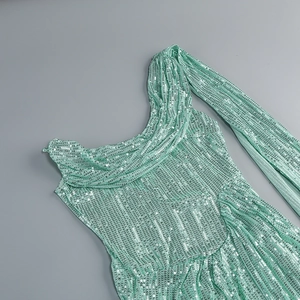 Close-up of mint green sequins on a pleated evening dress with metallic texture and shine