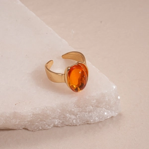 Detailed macro shot of vintage gold-tone ring with orange oval resin stone on stone