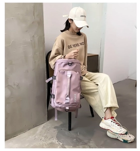 Detail of dusty pink nylon travel bag featuring front zipper pocket and side handle strap