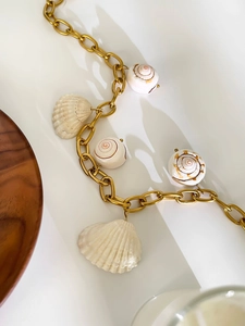 Detailed top view of a gold chain necklace featuring natural shell and conch pendants