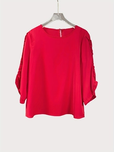 Detail shot of elegant red satin blouse featuring layered ruffle tiered sleeves on a white background