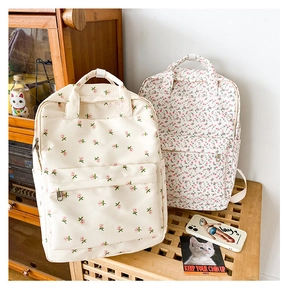 Close-up of vintage floral canvas backpacks with pink rose patterns and front zipper pockets