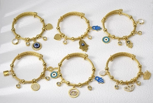 Detailed macro view of gold stainless steel cable bracelets with Hamsa and Evil Eye charms