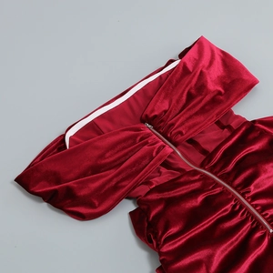 Détail du tissu en velours rouge plissé et zip métallique argenté d'une robe de soirée