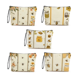Five assorted bee and floral print canvas makeup bags with black zippers and wrist straps
