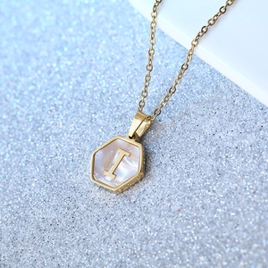 Hexagonal white shell letter I pendant in gold titanium steel on a sparkling surface