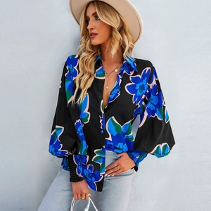 Dettaglio della camicia nera a maniche lunghe con stampa floreale blu e polsini elastici a balze