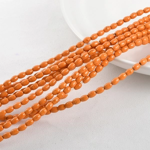 Macro view of oval orange synthetic turquoise beads for DIY jewelry on ceramic plate
