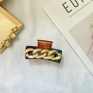 Detail of amber tortoiseshell hair claw clip with elegant gold chain link decoration