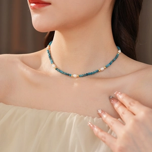 Close-up of blue beaded necklace with freshwater pearls and gold accents on model