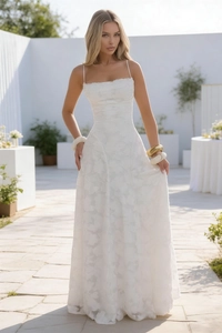 Detail of elegant white lace maxi dress featuring intricate floral embroidery and thin straps