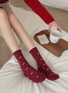 Detail of red cotton socks with white lace trim and tiny bows in a warm winter setting