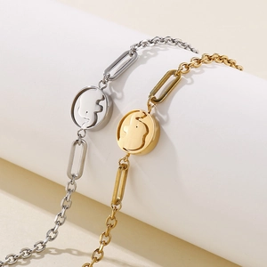 Elegant gold and silver elephant charm bracelets on minimalist white cylinder display