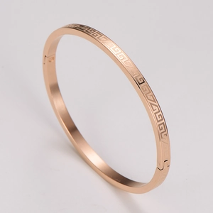 Close-up of rose gold bangle with Greek key pattern and a hinged opening detail