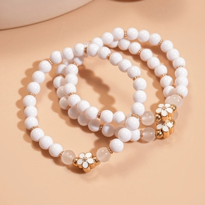Detailed macro view of three-piece beaded bracelet set with white enamel daisy charms