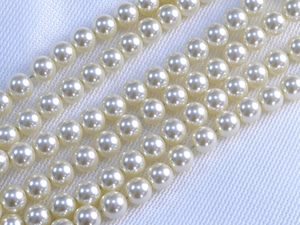 Macro shot of high-luster round white pearls on textured fabric for DIY jewelry