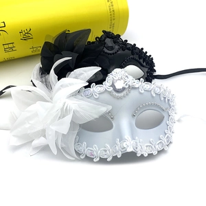 Detailed close-up of elegant black and white lace masquerade masks with feathers and flowers
