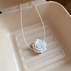 Détail d'un pendentif fleur de rose 3D blanche sur un collier à cordon fin minimaliste