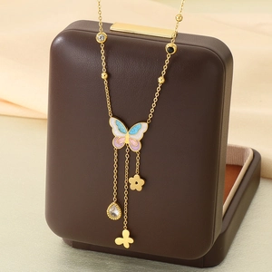 Golden butterfly necklace with enamel wings, floral charms, and teardrop crystal pendant
