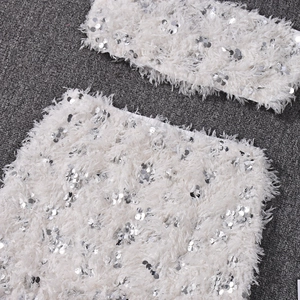 Detail of silver sequined crop top and feather skirt set on grey textured background