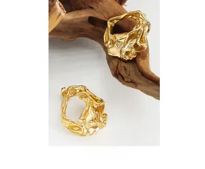 Close-up of gold stud earrings with a unique crumpled metal texture and irregular shape
