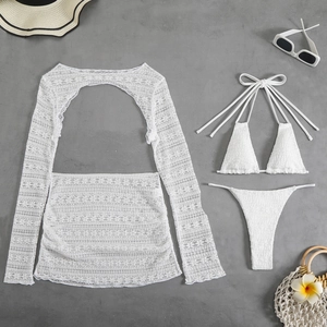 Flat lay detail of white lace cover-up with textured bikini set and summer beach accessories